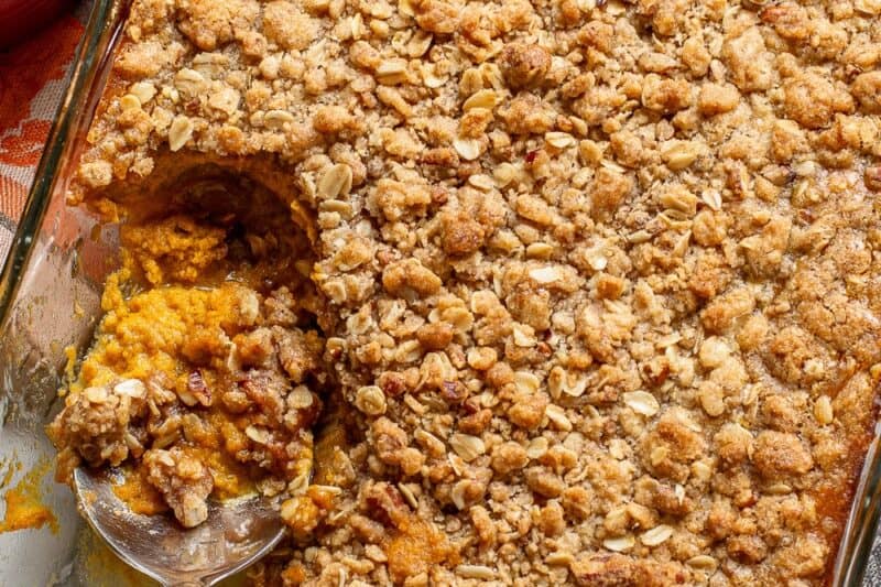 A pumpkin crisp in a large pan with a spoonful being scooped out.