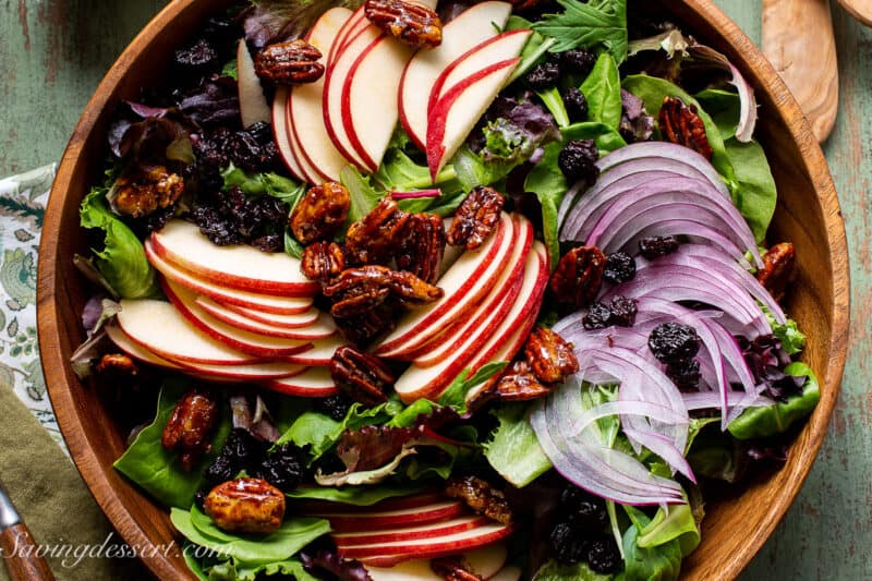 An overhead view of a bowl of salad with sliced apples and onions