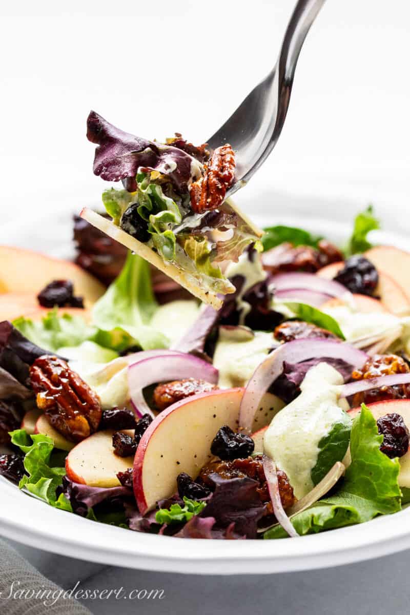 A plate filled with apple salad with a fork scooping up a bite.