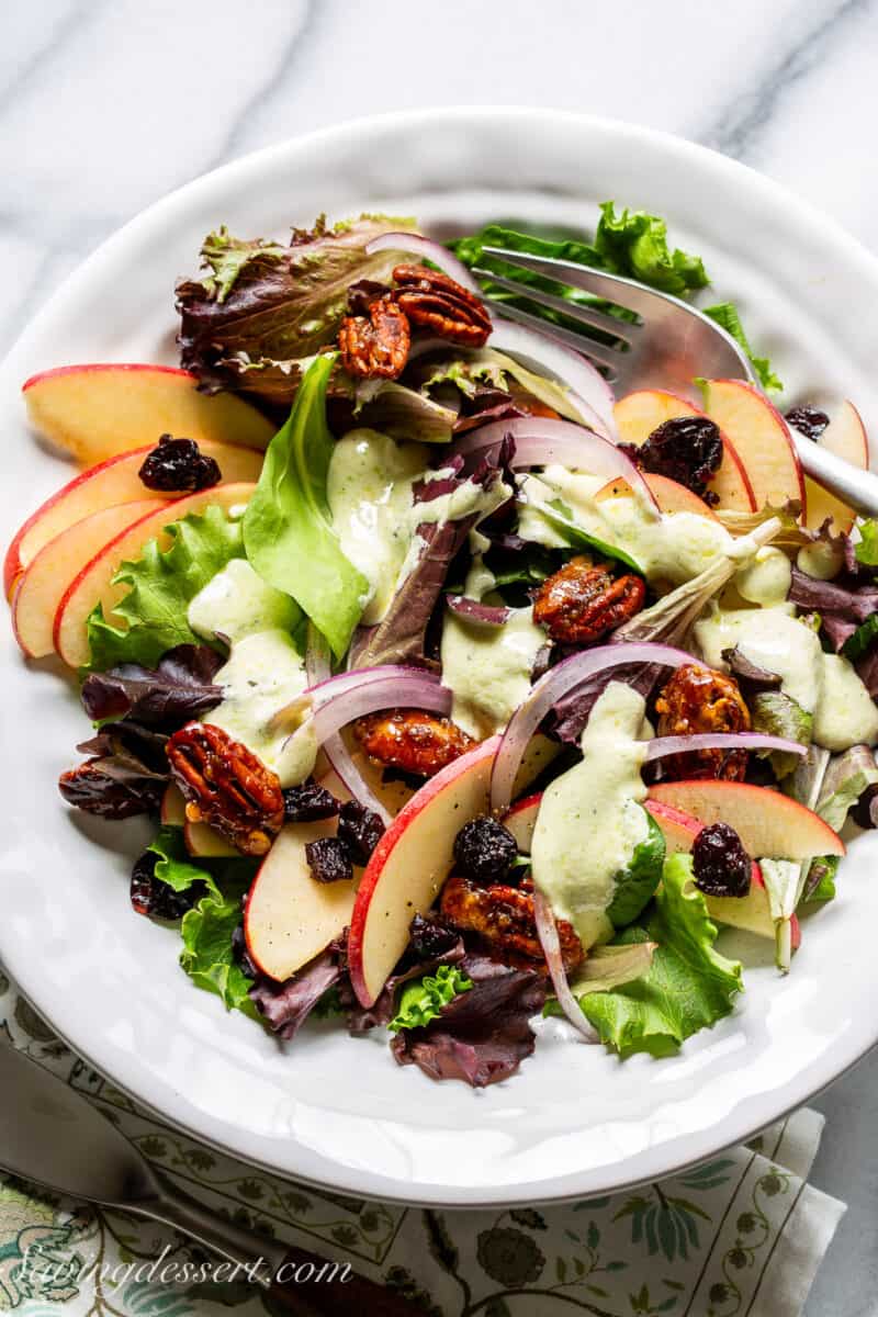 Apples onions and dried cherries on a bed of salad greens drizzled with a creamy feta dressing.