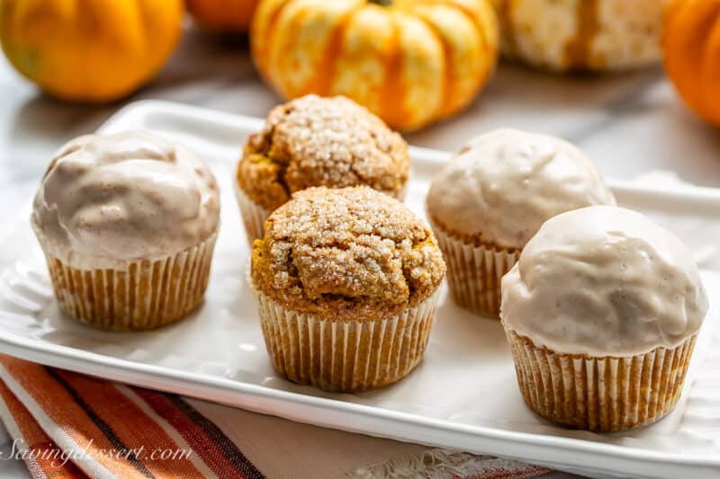 A small platter of pumpkin muffins some with a sugar topping and others dipped in a glaze.