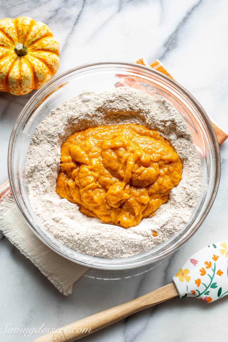 A bowl of dry ingredients with canned pumpkin in the center.