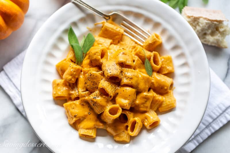 An overhead view of a bowl of pasta with a creamy cheesy pumpkin sauce and fresh sage.