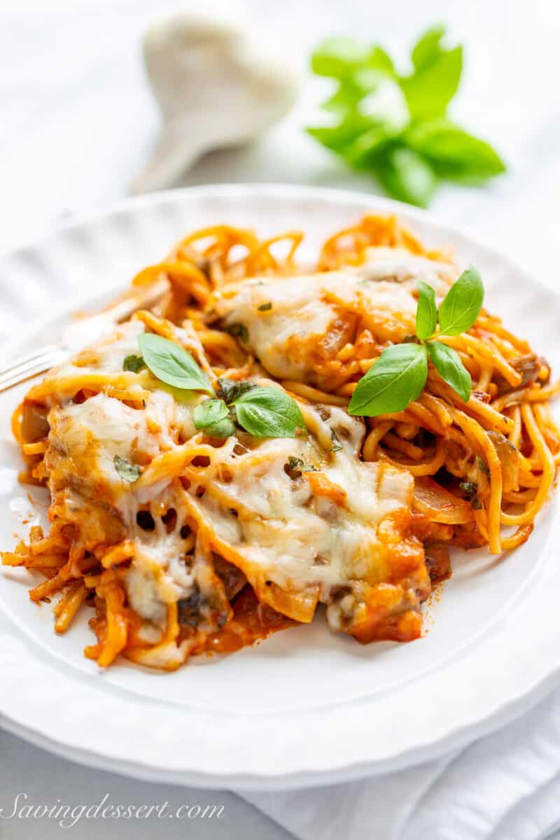 A plate filled with spaghetti topped with fresh basil and lots of cheese.