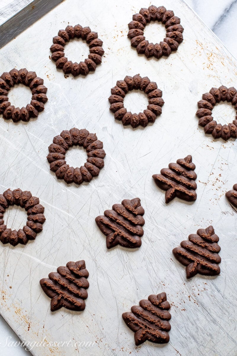 A cookie sheet filled with piped chocolate spritz cookies ready to bake.