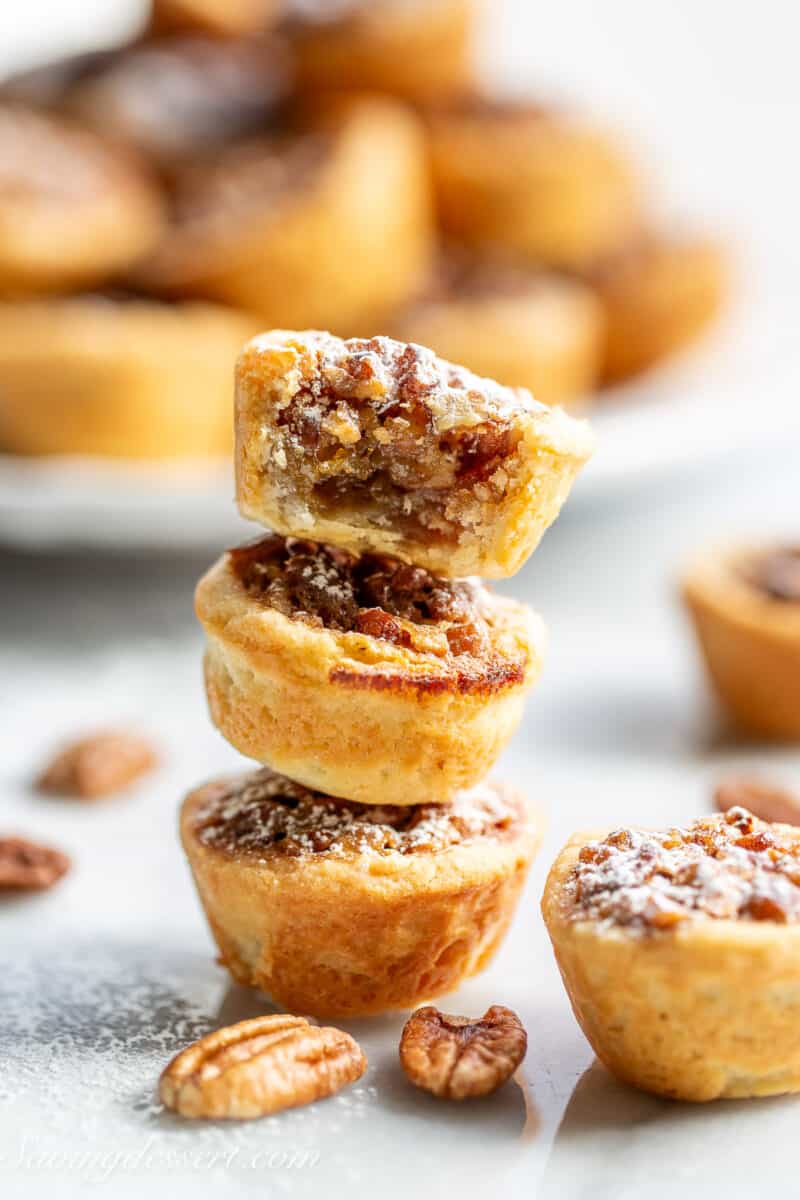 A stack of three pecan tassies with the top tassie partially eaten to show the middle.