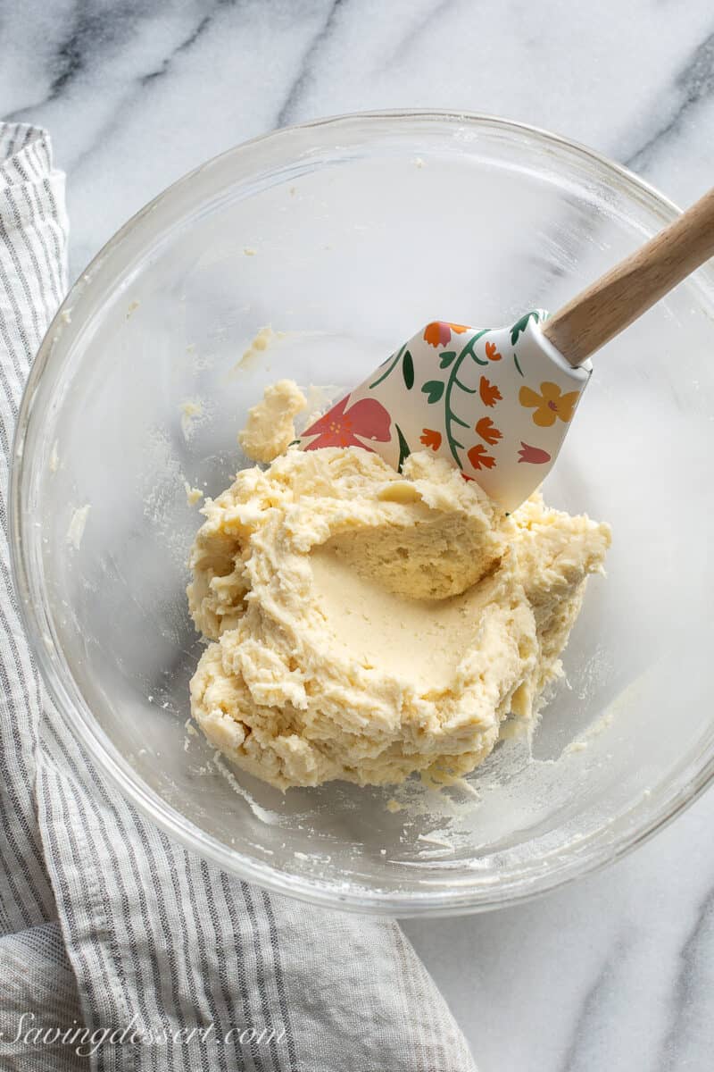 A mixing bowl with cream cheese cookie dough and a spatula.