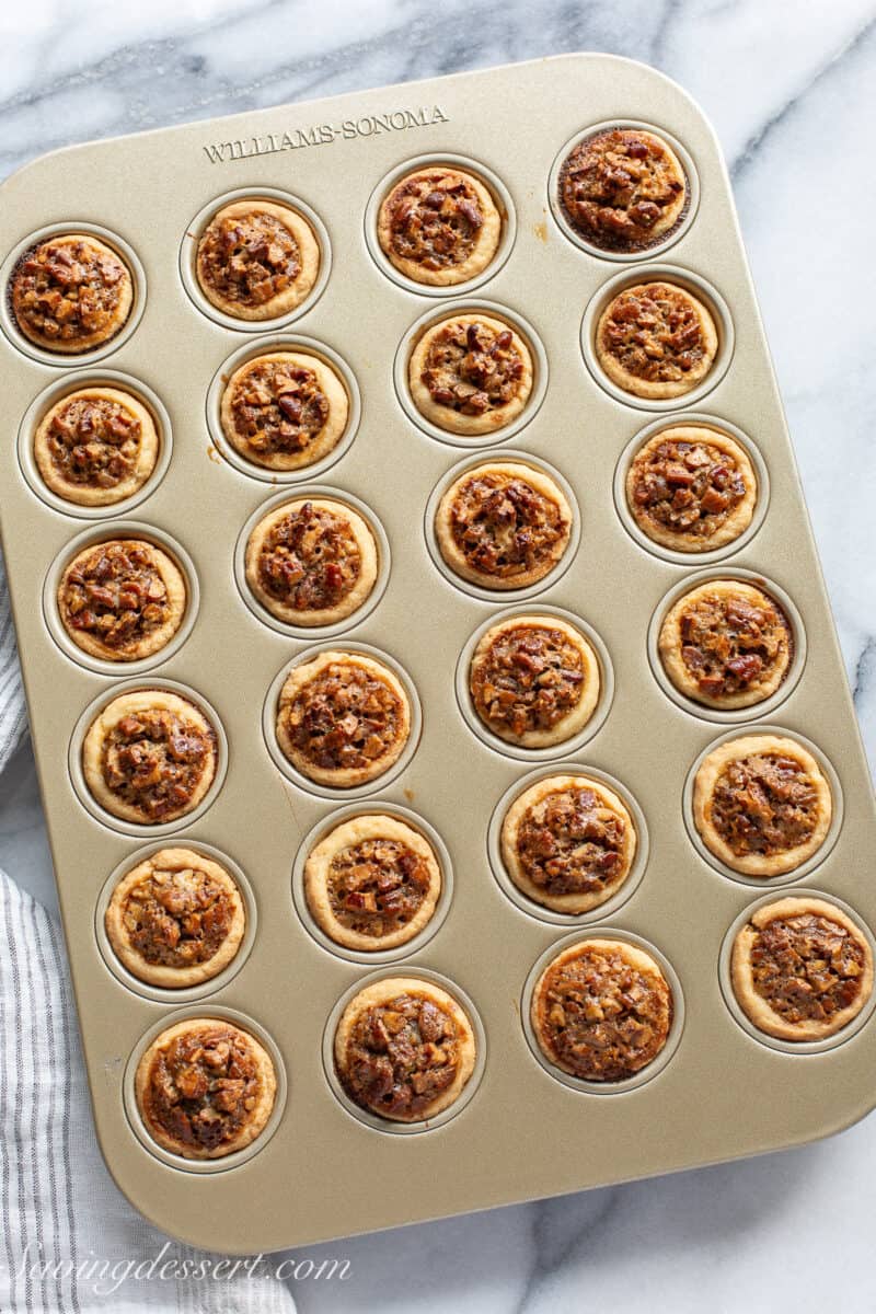 Hot from the oven pecan tassies in a mini muffin tin.