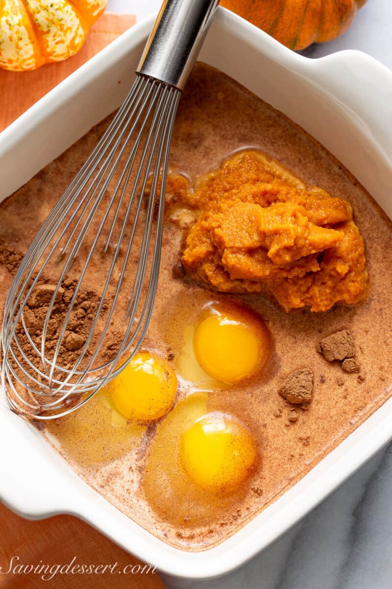 A baking dish filled with eggs, pumpkin puree, spices, milk and sugar.