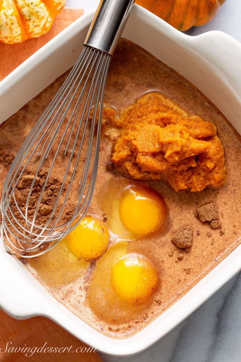 A baking dish filled with eggs, pumpkin puree, spices, milk and sugar.