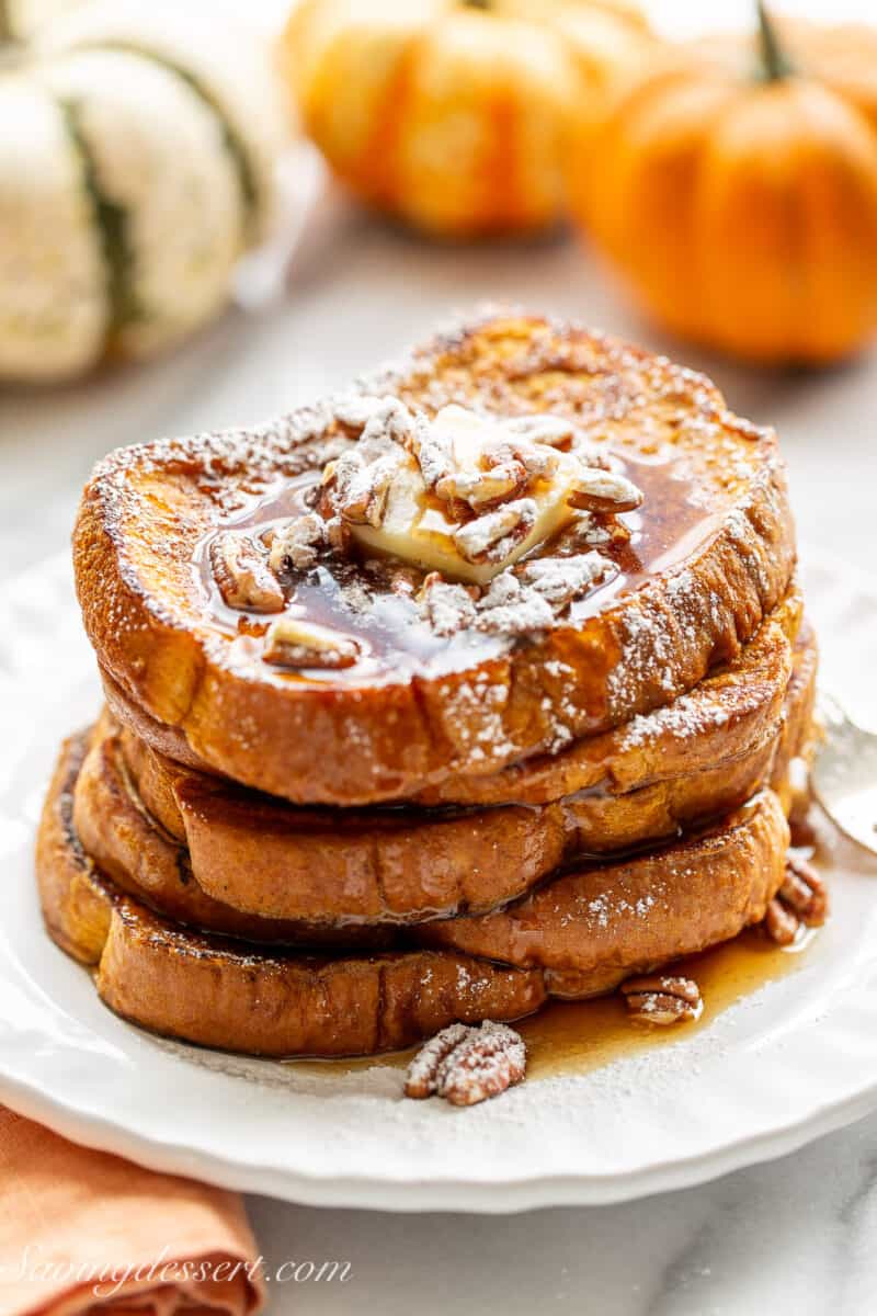 Slices of French Toast on a plate with syrup and pecans on top.
