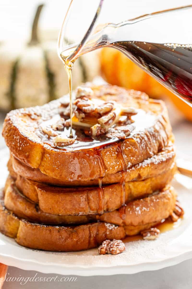 A stack of French toast being drizzled with maple syrup.