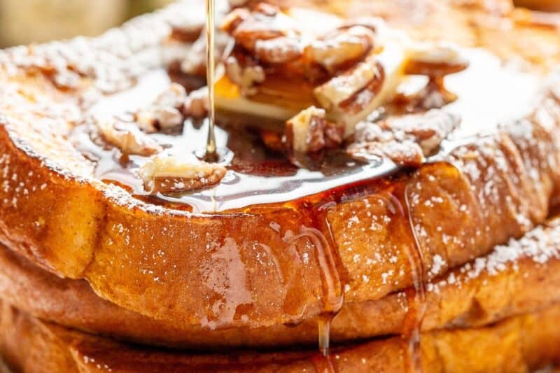 Side view of a stack of Pumpkin French Toast being drizzled with syrup.