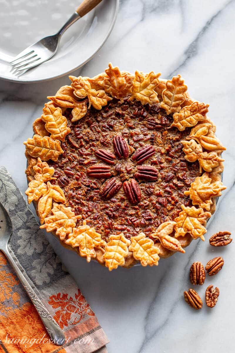 An overhead view of a whole pecan pie decorated with cookie crust leaves.