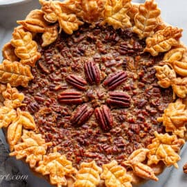 An overhead view of a pecan pie with cookie crust cutouts in the shape of leaves.