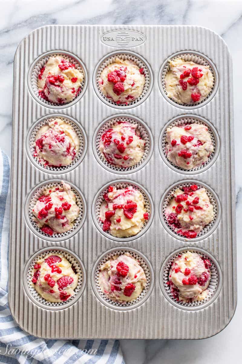 Raspberry muffin batter in a muffin tin ready to bake.