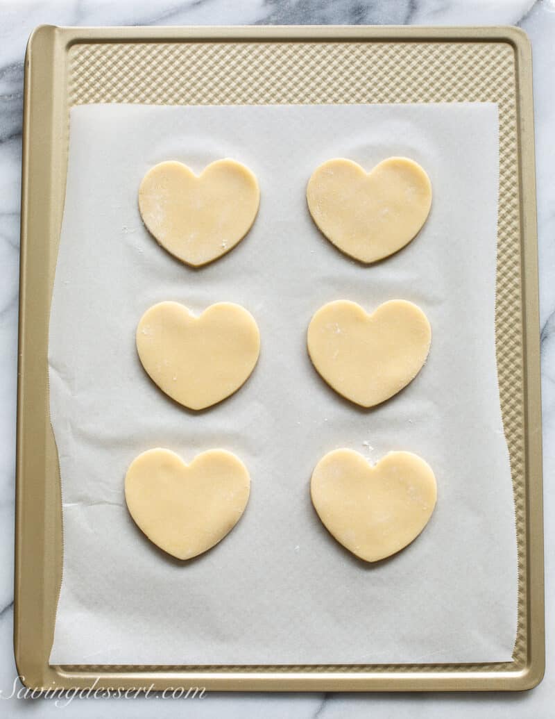 A cookie sheet with heart shaped cookies cut out and ready to bake.