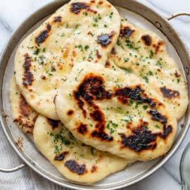 An overhead shot of a few naan breads brushed with parsley butter.