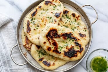 An overhead shot of a few naan breads brushed with parsley butter.