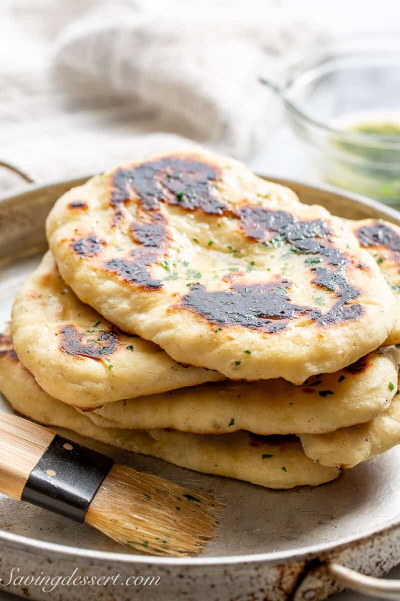 Fresh homemade naan bread stacked in a pan.