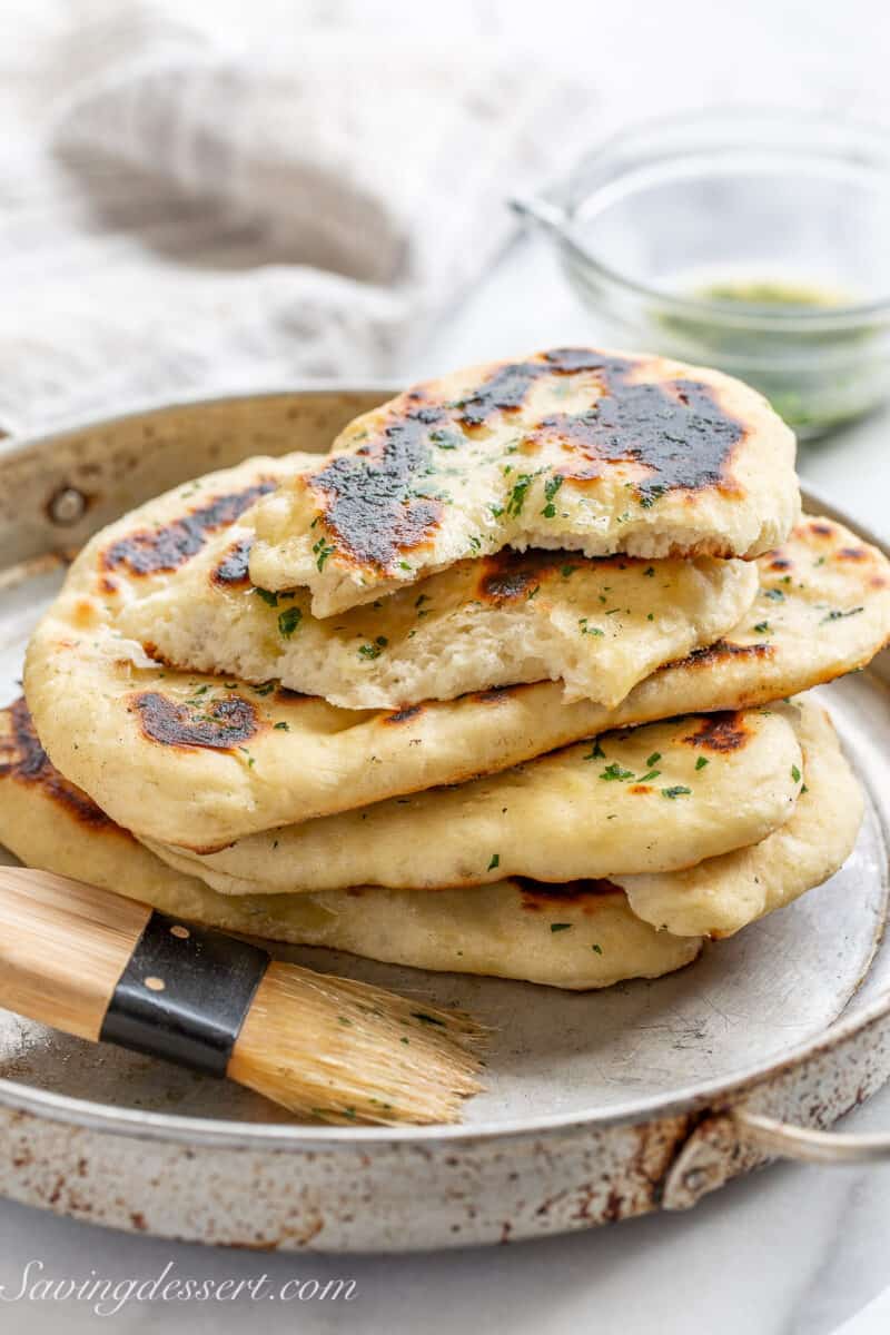 A pan with a few naan bread rounds stacked on top of each other with one halved on top.