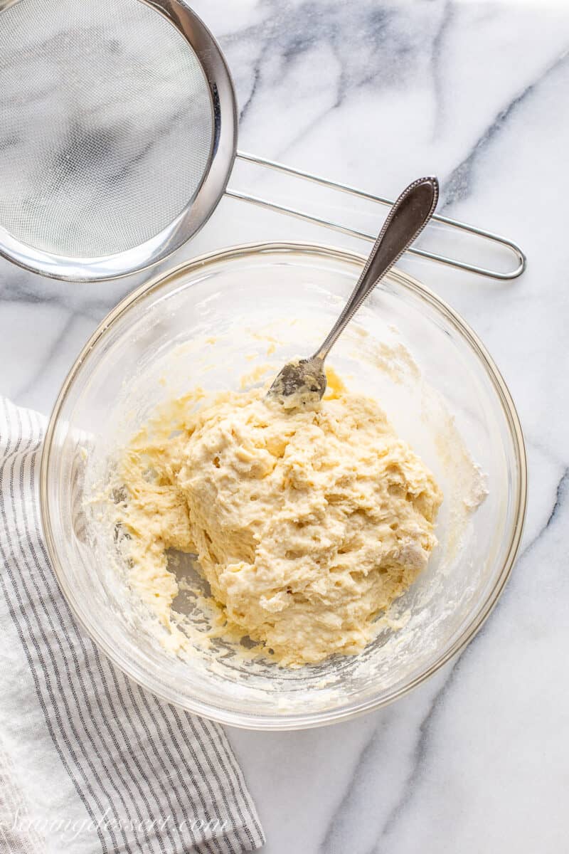 An overhead view of a bowl filled with yeast dough with a fork for mixing.