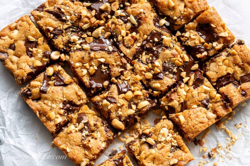Peanut Butter Blondies cut into squares garnished with dark chocolate and chopped roasted peanuts.