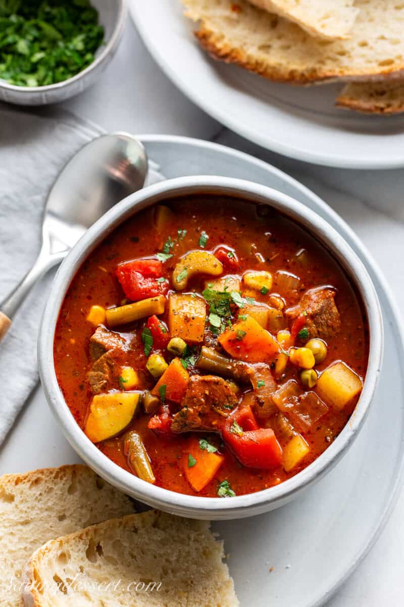 An overhead photo with a big bowl of soup with bread and parsley on the side.