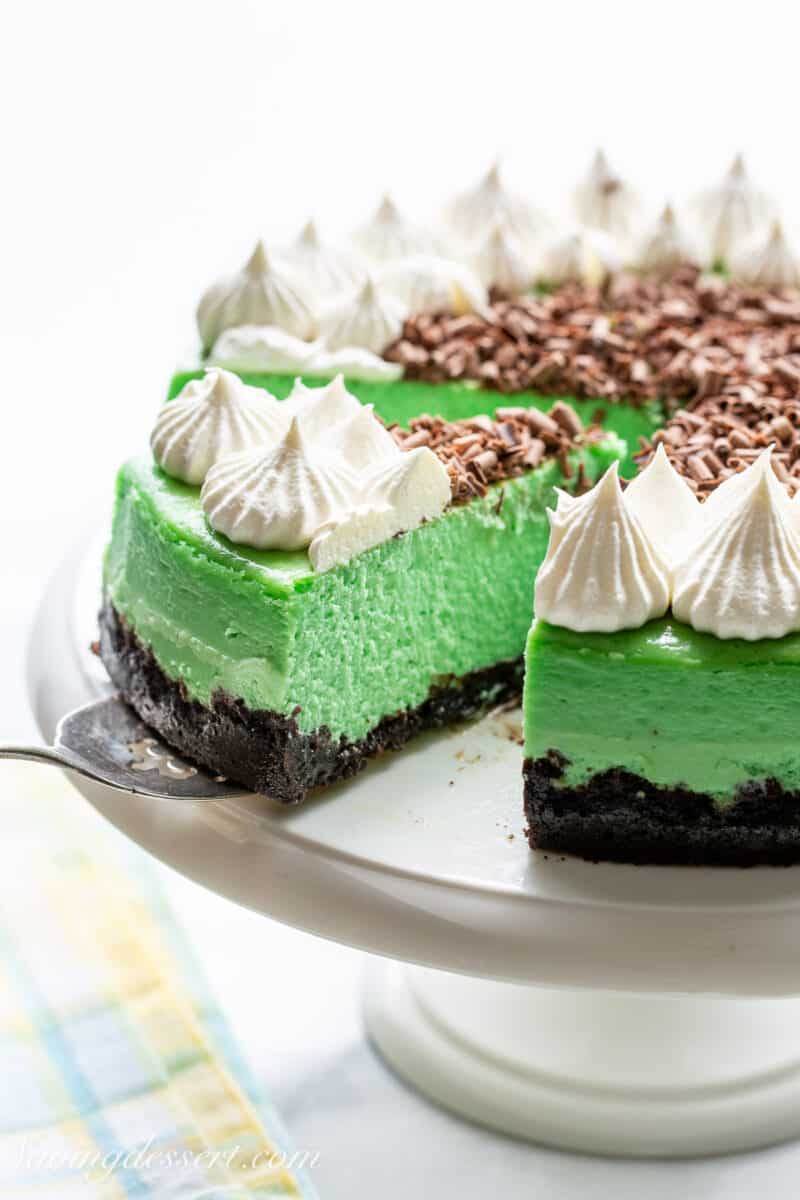 A slice of grasshopper cheesecake being removed from a cake platter.