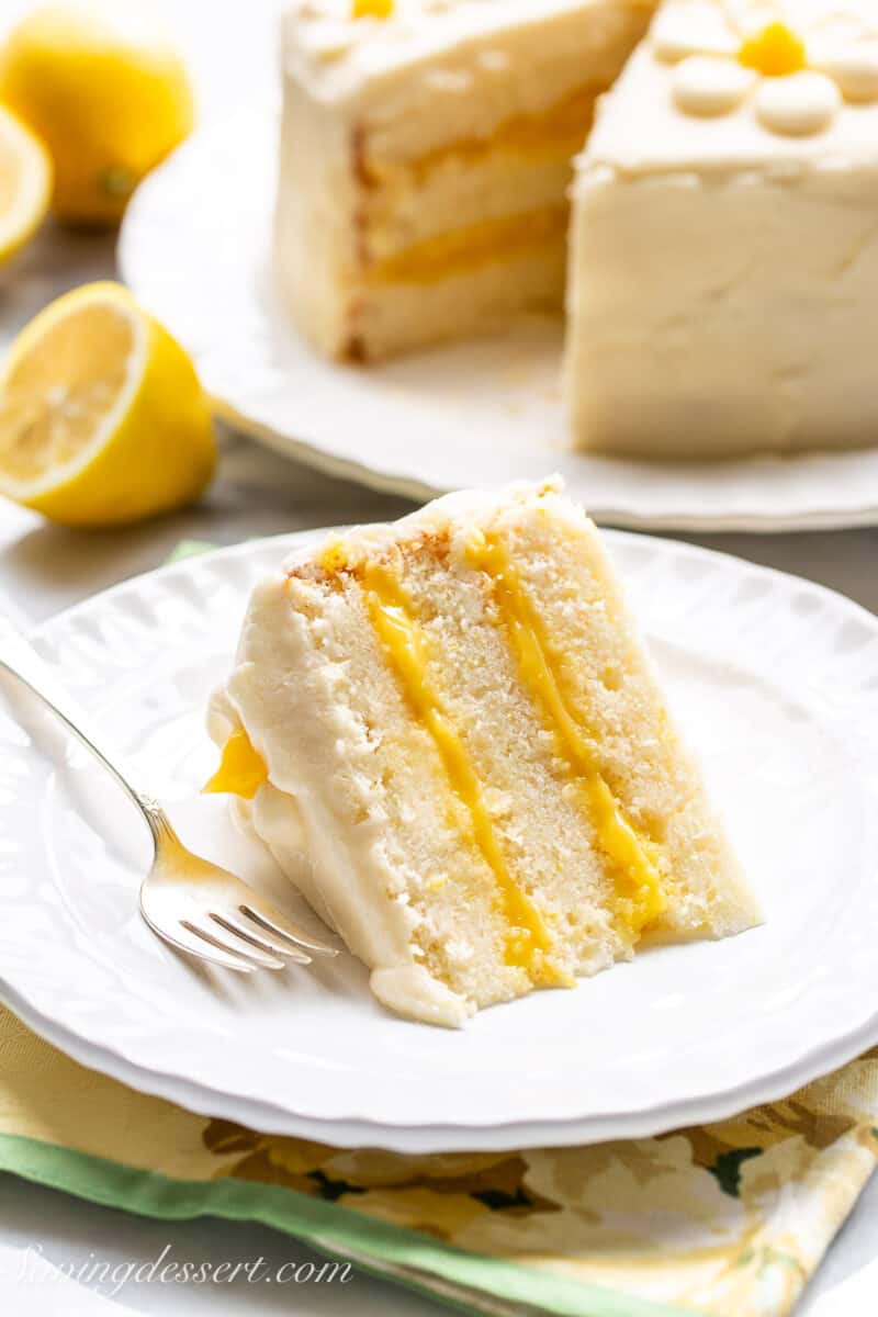 A slice of lemon curd cake on a plate with a fork.