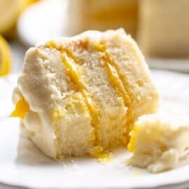 A slice of partially eaten lemon curd cake on a plate with a fork.