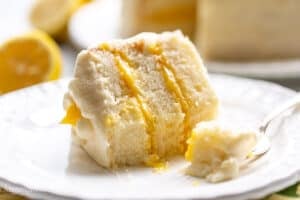 A slice of partially eaten lemon curd cake on a plate with a fork.