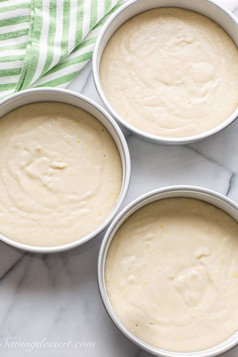 Three 8-inch cake pans filled with lemon cake ready to go in the oven.