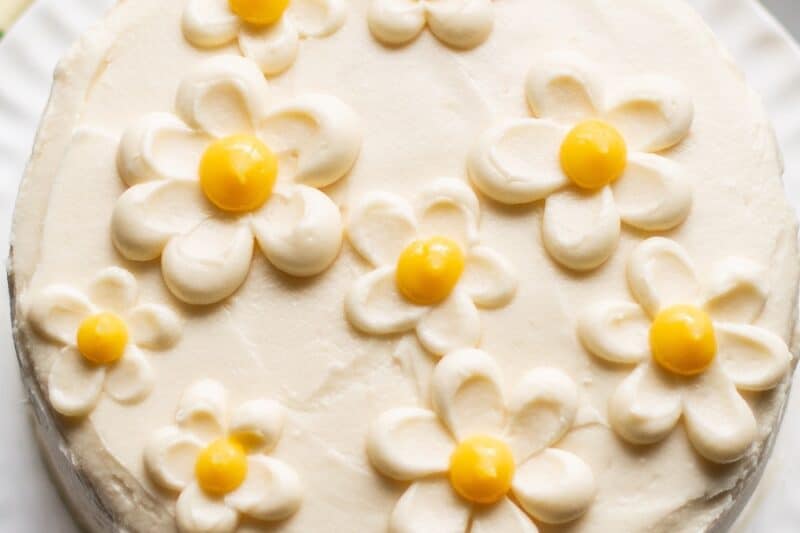 An overhead shot of a pretty lemon curd cake with buttercream flowers on top.