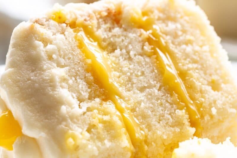 A closeup of a slice of lemon curd cake on a plate.