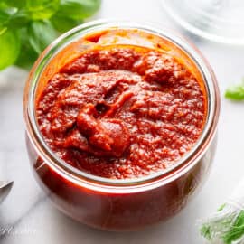 An overhead shot of a large wide mouth jar of homemade pizza sauce.