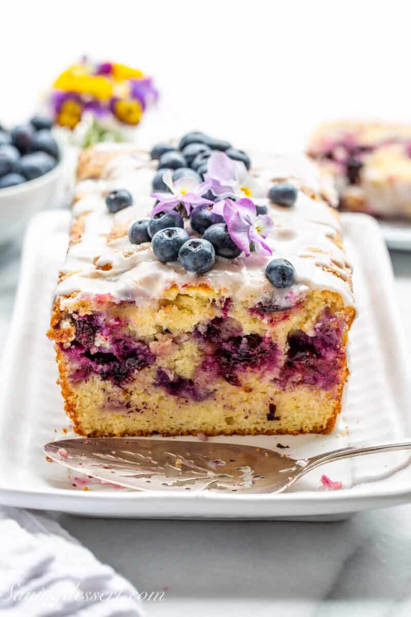 A side view of a sliced loaf of blueberry bread on a platter.