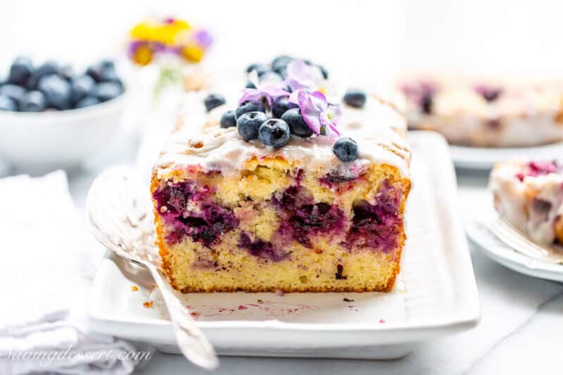 A side view of a sliced loaf of blueberry lemon bread.