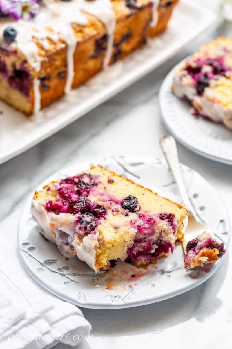 A slice of blueberry lemon bread on a plate with a fork.