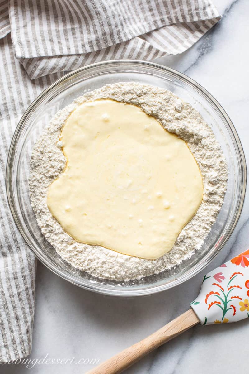A bowl filled with a flour mixture with wet ingredients mixed and poured into the middle.