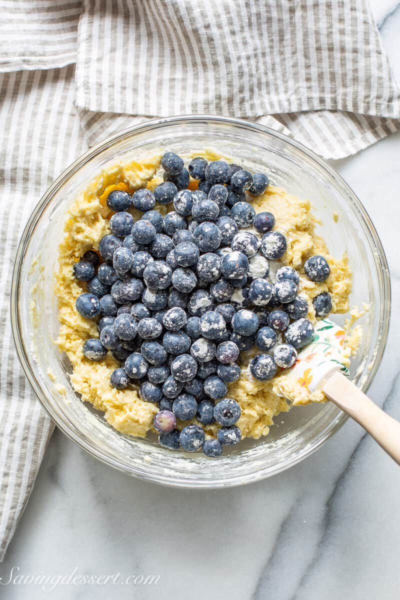 Lemon Bread batter in a bowl topped with fresh blueberries to be mixed in.