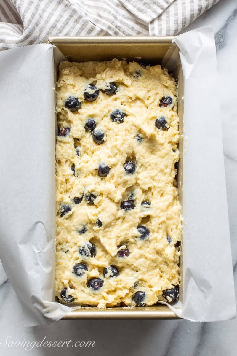A loaf pan filled with blueberry bread batter.