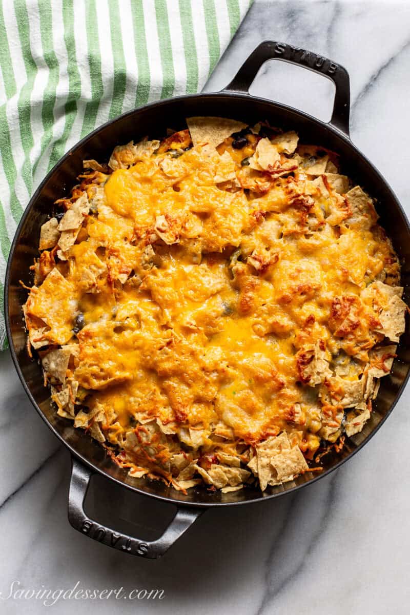 A skillet with a cheesy casserole with tortillas chips.