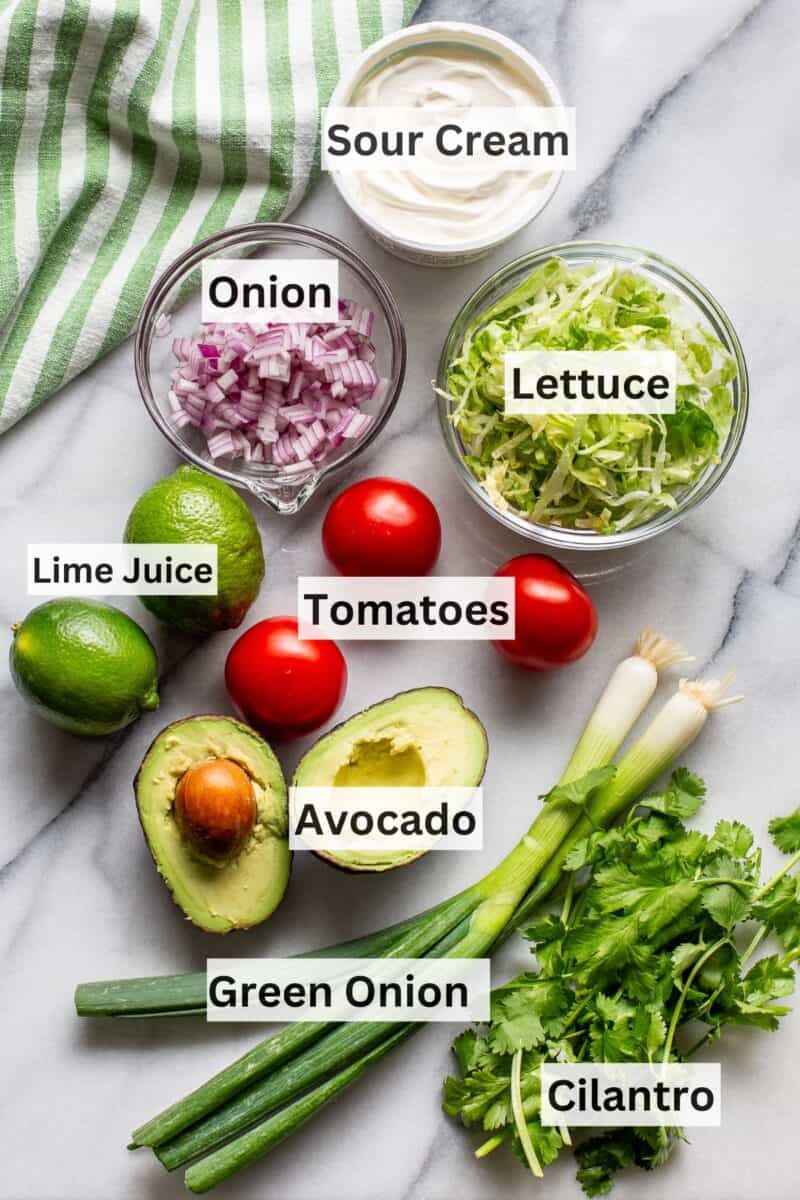 A collage of ingredients used for topping tacos and casseroles like green onions, avocado, tomato, lettuce, onions and sour cream.