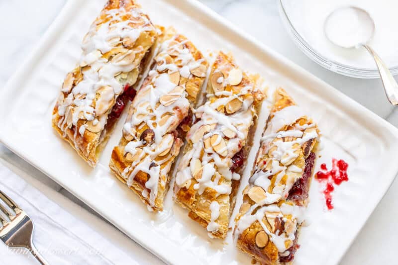 An overhead view of a small platter with four pieces of an almond raspberry breakfast pastry.