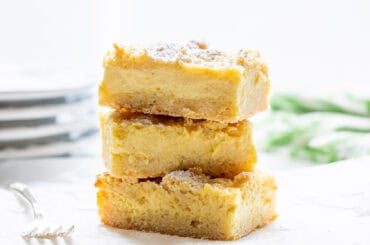 A stack of lemon crumb bars topped with powdered sugar.