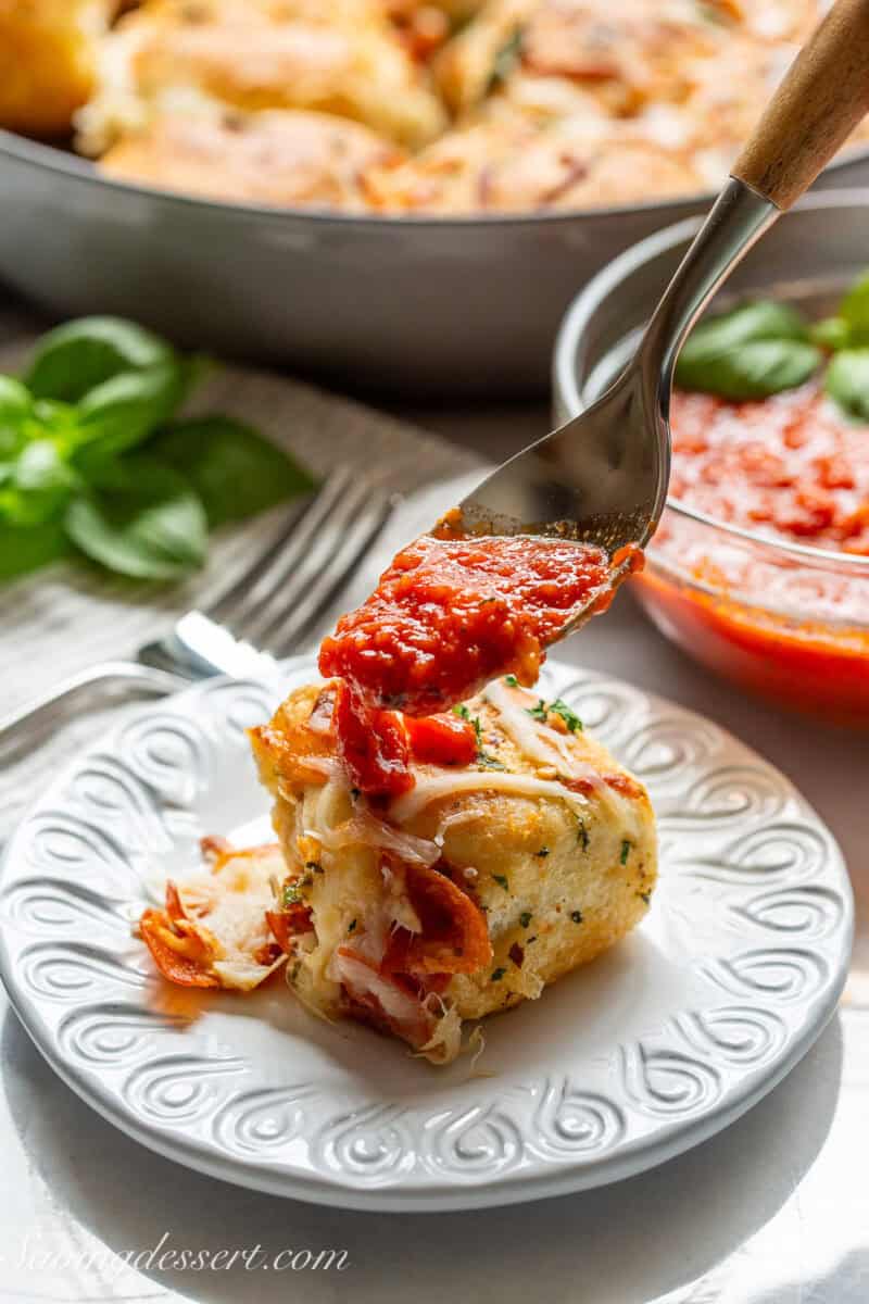 A pull apart pizza roll being covered in pizza sauce.