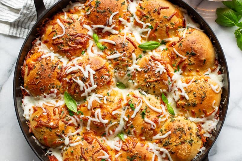A skillet filled with pull apart pizza bread.