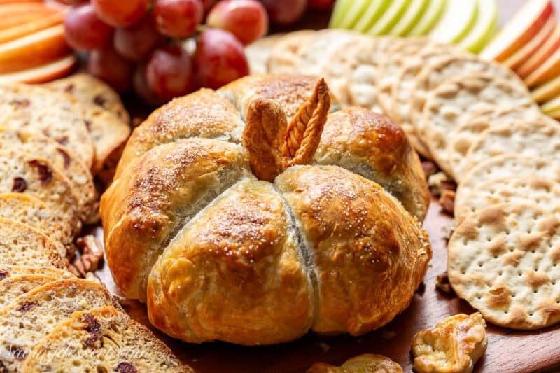 A wheel of baked brie covered in puff pastry to mimic a small pumpkin.