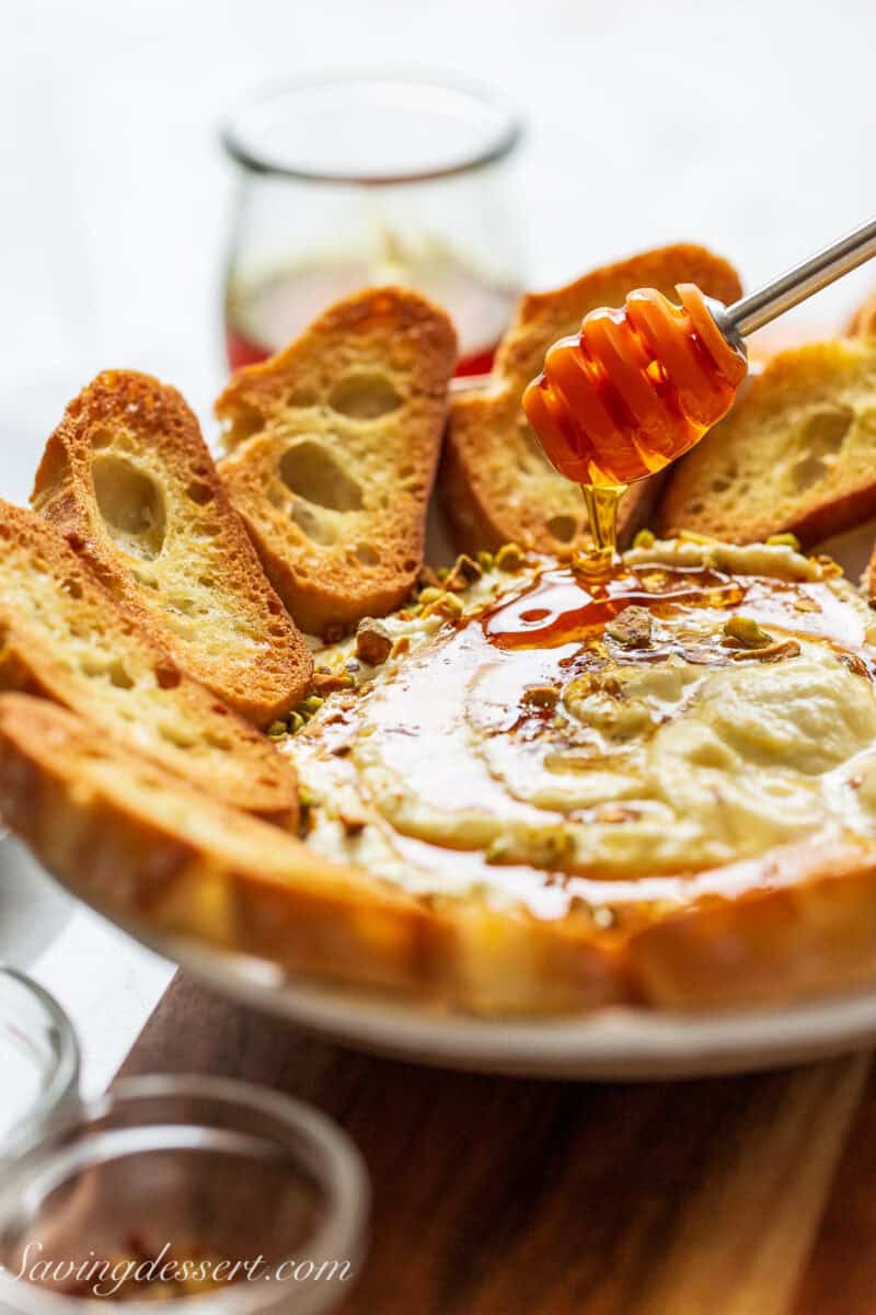 A bowl of whipped feta dip being drizzled with honey.